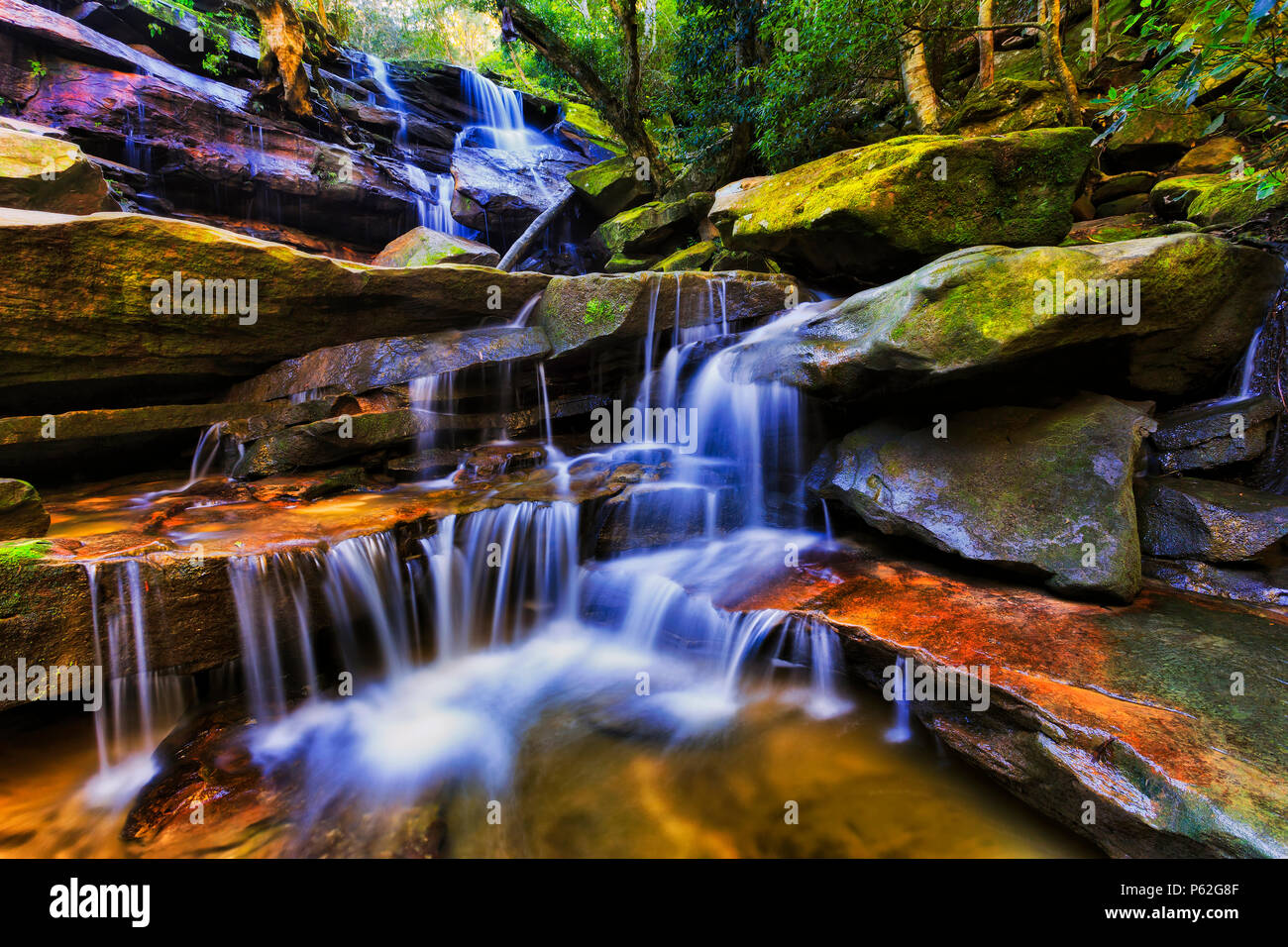 Wide strong Somersby waterfall down in rainforest creek of central coast NSW after heavy raines flowing between sandstone rocks. Stock Photo