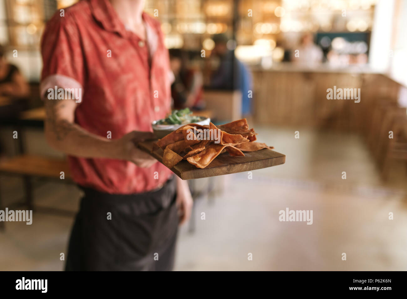 Waiter serving up a board of freshly baked nachos Stock Photo