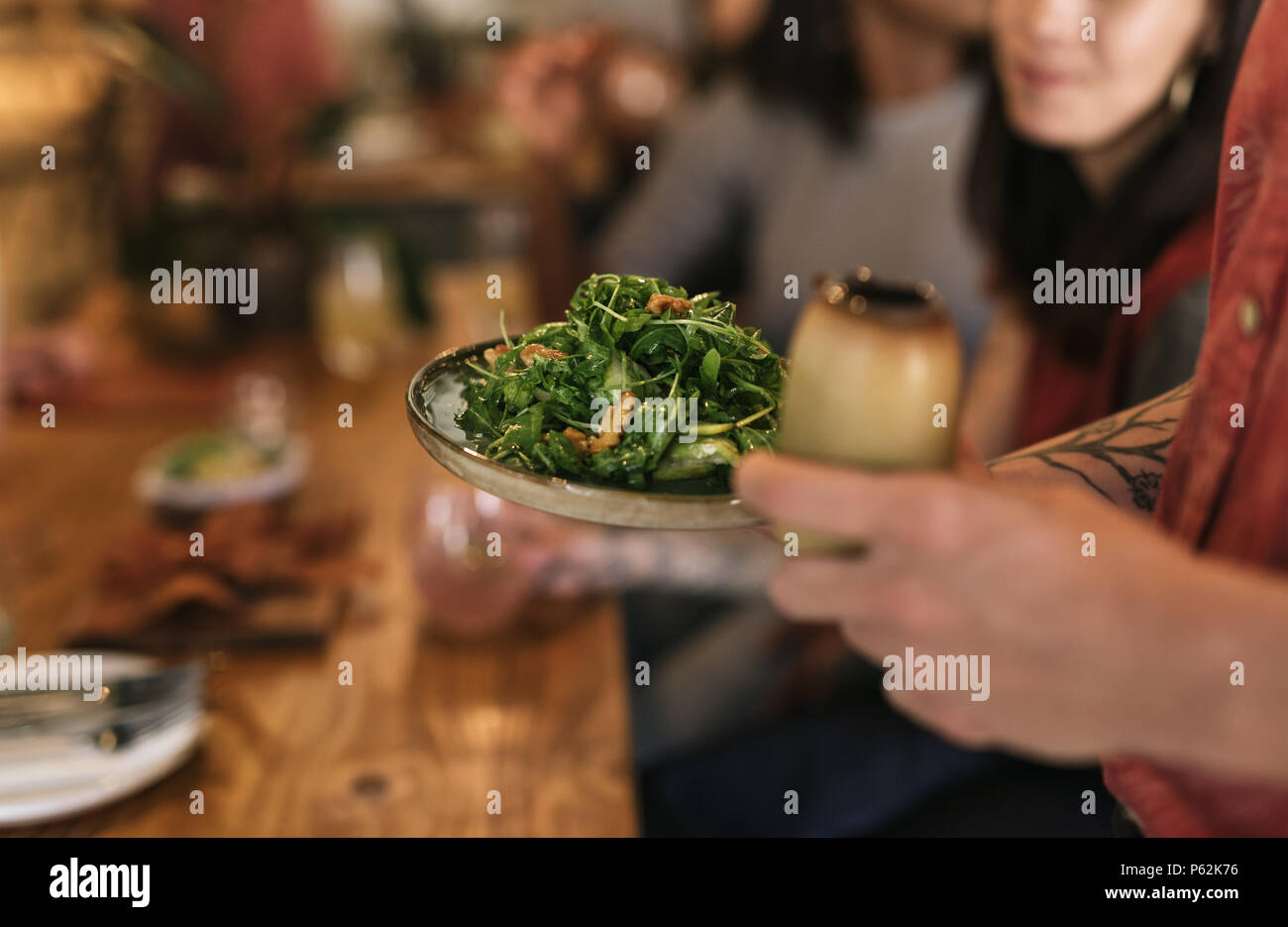 Waiter serving a healthy salad to bistro customers Stock Photo