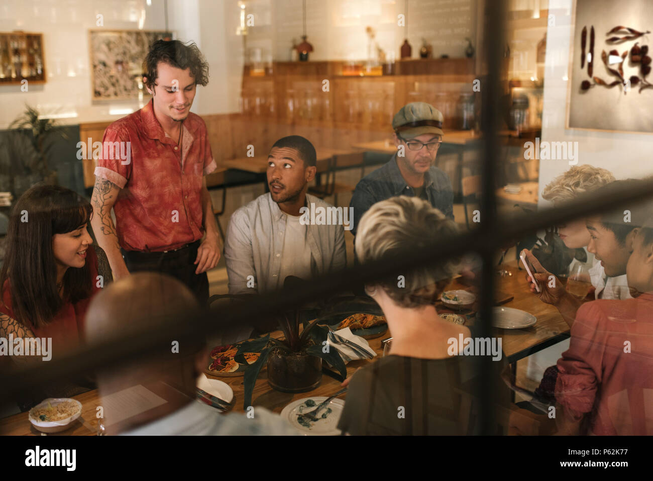 Smiling waiter talking with customers inside a trendy bistro Stock Photo