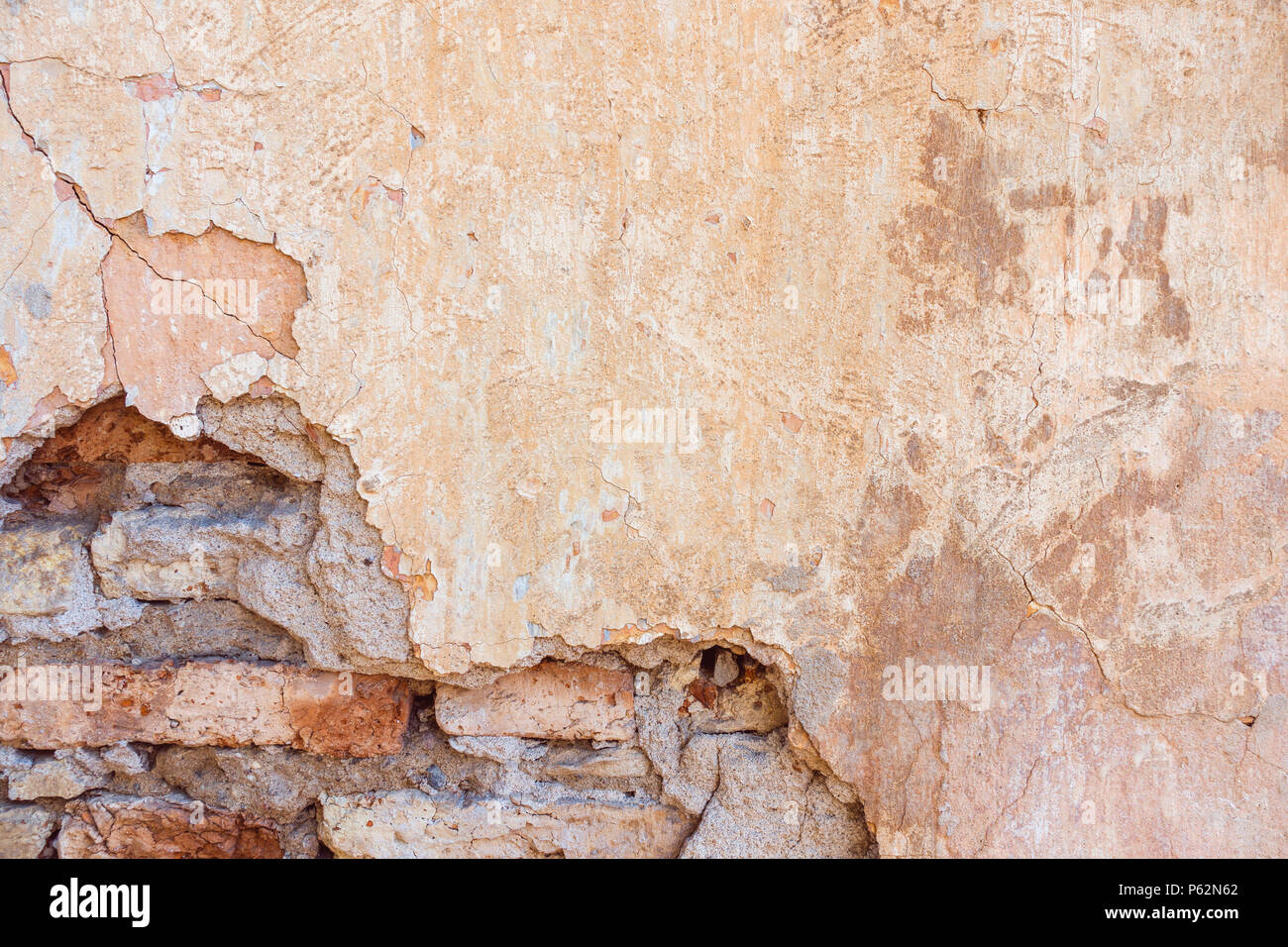 Old Cracked Weathered Shabby Yellow Painted Plastered Peeled Brick Wall Background. Stock Photo