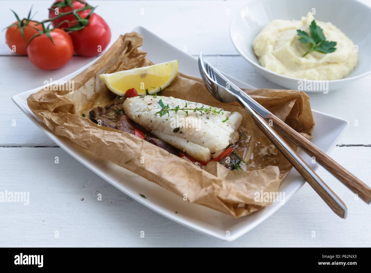 Cod fillets baked in parchment paper with vegetables Stock Photo