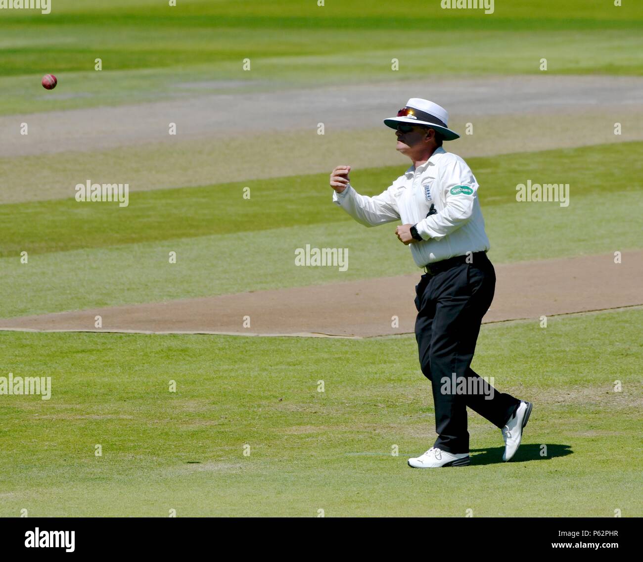 The umpire throws the ball to the bowler after examining it after it had been hit under a spectator's stand. Stock Photo