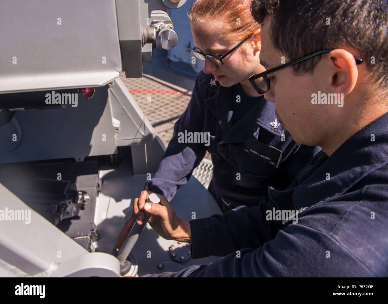 20160403-N-FV739-060  PACIFIC OCEAN (April 3, 2016) – Gunner’s Mate 3rd Class Yeison Bobadilla and Gunner’s Mate 3rd Class Claire Meyers perform maintenance on 25mm Mk 38 Mod 2 machine gun system on the fantail of guided-missile cruiser USS Port Royal (CG 73) during an independent deployer certification exercise (IDCERTEX). The IDCERTEX is designed to certify select U.S. ships as independent deployers as tasked by Commander, U.S. 3rd Fleet. (U.S. Navy photo by Mass Communication Specialist 3rd Class Christopher A. Veloicaza/Released) Stock Photo