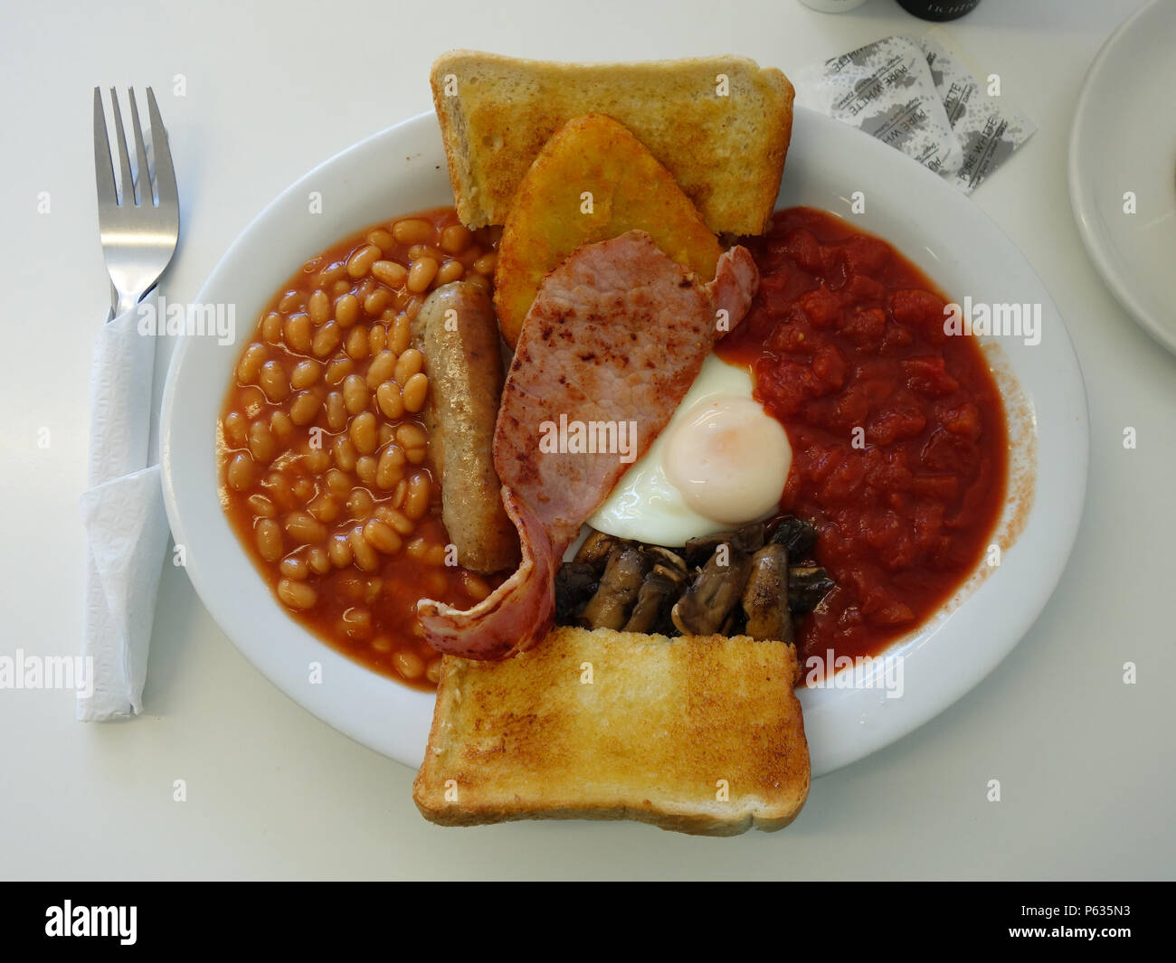 Full English all day Breakfast in a Sheffield cafe. Bacon, Egg, Tinned Tomatoes,Hash Browns, Beans, Sausage, Mushrooms with toast and of course a good Stock Photo
