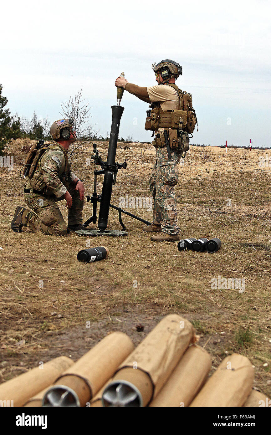 A Latvian special forces soldier hangs an 81mm mortar round at the command  of a Special Operations Command Forward Eastern Europe soldier during  weapons familiarization training, April 13, at Adazi Military Base,