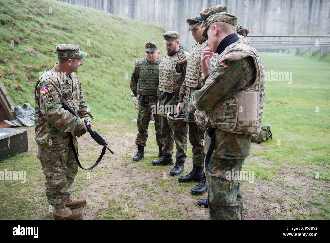 U.S. Army Sgt. 1st Class Randy Frehill, with Alpha Company, Allied Forces North Battalion, U.S. Army NATO Brigade, describes the M4 carbine that German Soldiers assigned to Joint Forces Command Brunssum will qualify with in the Dutch Army outdoor firing range in Budel, the Netherlands, April 13, 2016. This qualification session lead by Alpha Company was the first with participation of Allied forces assigned to JFC Brunssum. (U.S. Army photo by Visual Information Specialist Pierre-Etienne Courtejoie/Released) Stock Photo