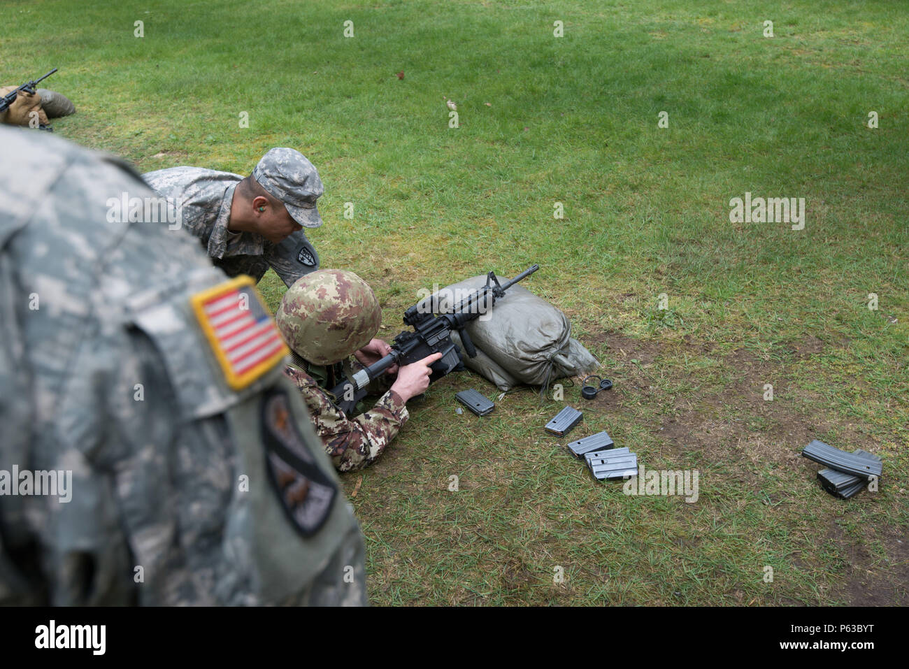 U.S. Army Staff Sgt. Jeniel Gamponia, with Alpha Company, Allied Forces North Battalion, U.S. Army NATO Brigade, assists an Italian Soldier assigned to Joint Forces Command Brunssum who performs M4 carbine qualification in the Dutch Army outdoor firing range in Budel, the Netherlands, April 13, 2016. This qualification session led by Alpha Company was the first with participation of Allied forces assigned to JFC Brunssum. (U.S. Army photo by Visual Information Specialist Pierre-Etienne Courtejoie/Released) Stock Photo