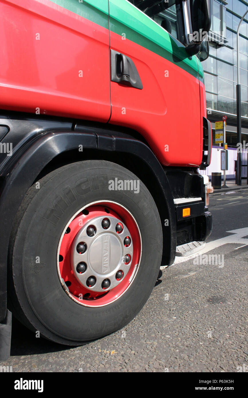Oblique view of front of red lorry showing tyre and cab unit. Stock Photo