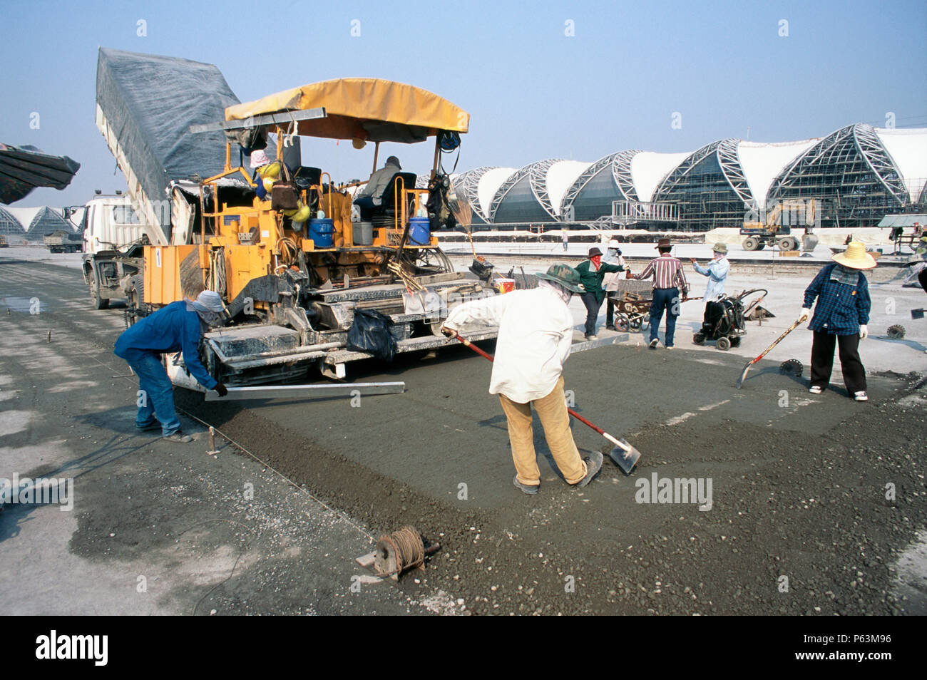 Concrete paving machine and crew working on the hardstand areas for the planes near the terminal