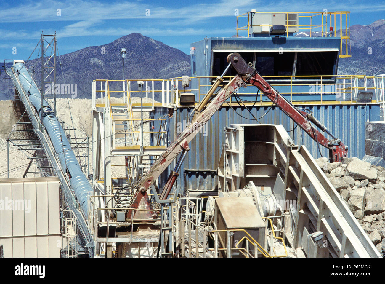 Gold ore is stokpiled by conveyor for cyanide wash extraction on a gold mine in the Nevada desert USA after rock ore crushing (foreground) Stock Photo