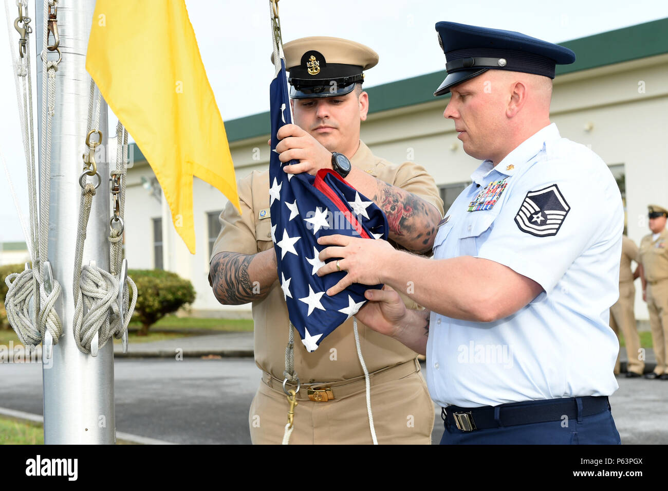 150401-N-DH124-009  OKINAWA, Japan (Apr. 1, 2016) - Chief Gunner’s Mate Joseph Hourieh (left) and U.S. Air Force Master Sgt. Martin Grant (right) prepare to raise the National Ensign as the members of the Naval Mobile Construction Battalion (NMCB) 4 Chiefs Mess participate in morning colors to celebrate 123 years of deckplate leadership in Okinawa, Japan, Apr. 1.  (U.S. Navy photo by Mass Communication Specialist 1st Class Rosalie Chang/Released) Stock Photo