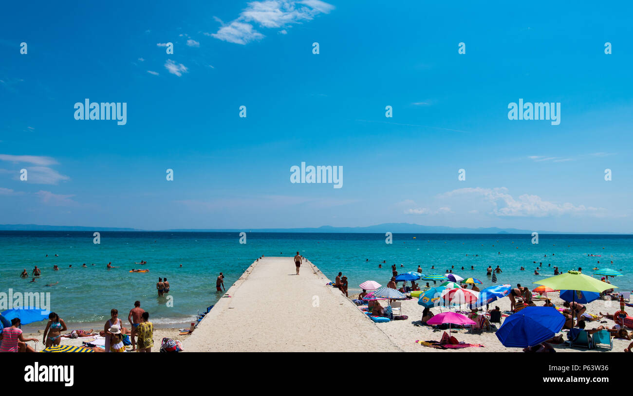 Chaniotis, Greece - June 23, 2018: Chaniotis city beach and clear sea of Chalkidiki with many tourists, Greece seaside destination Stock Photo
