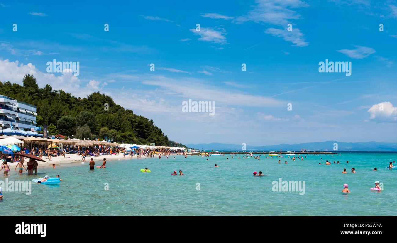 Chaniotis, Greece - June 23, 2018: Popullar Chaniotis city beach in Kassandra, Chalkidiki with many tourists enjoying the sunny day Stock Photo