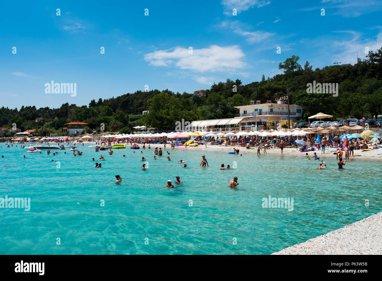 Chaniotis, Greece - June 23, 2018: Popullar Chaniotis city beach in Kassandra, Chalkidiki with many tourists enjoying the sunny day Stock Photo