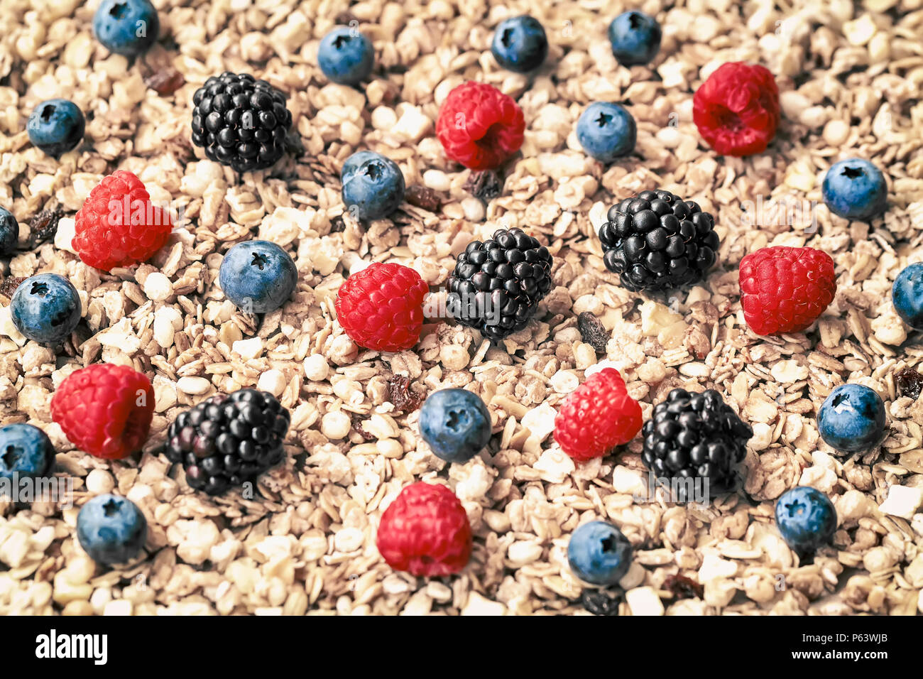 Raspberry, blueberries, blackberries on background of muesli, Oat flakes, granola. Healthy breakfast, right lifestyle, detox, vitamins, dieting organic vitamins Stock Photo
