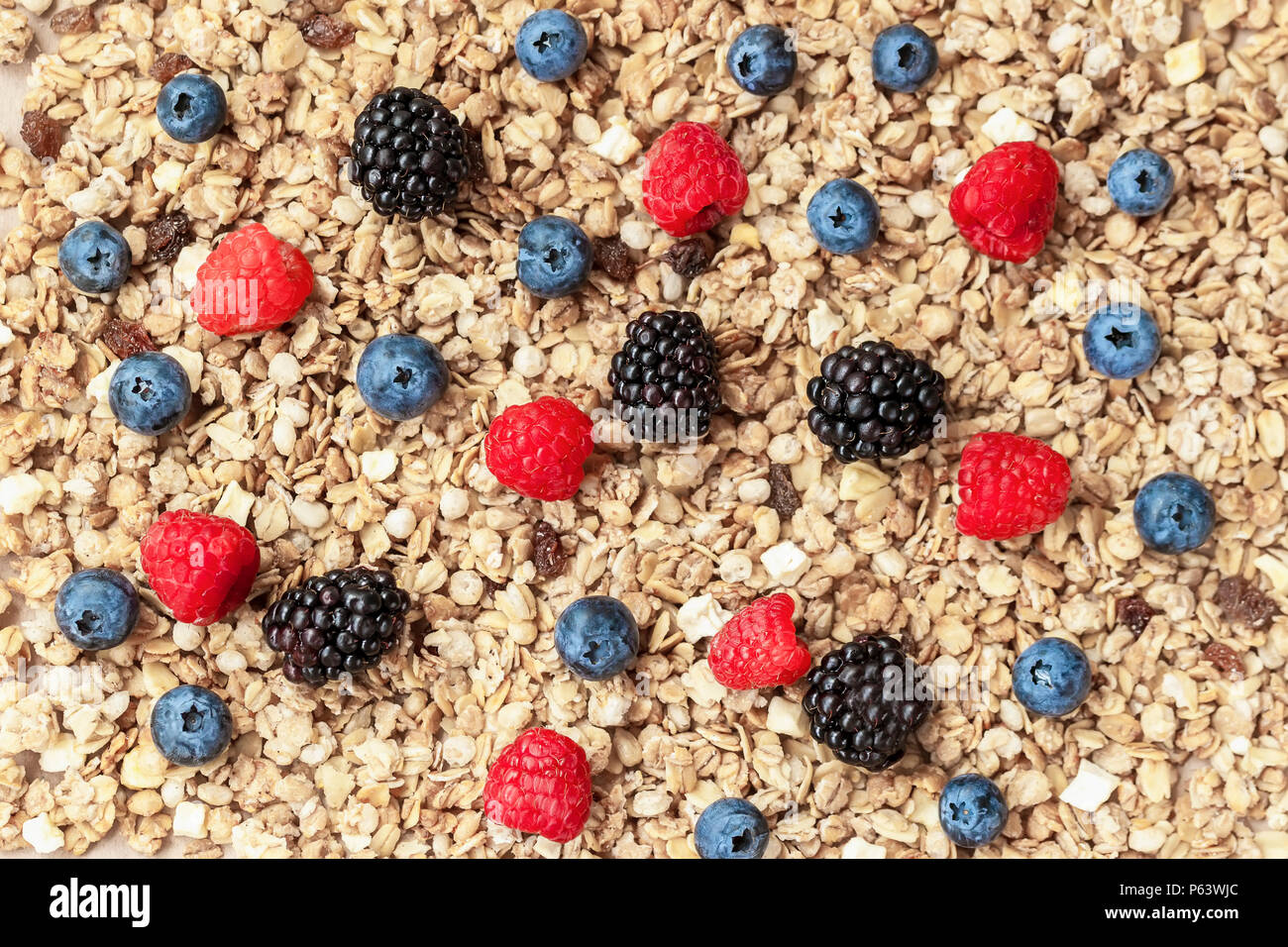 Oat flakes, granola, muesli and berries. Raspberry, blueberries, blackberries close-up on background of muesli. Healthy breakfast, right lifestyle, vitamins, dieting Stock Photo