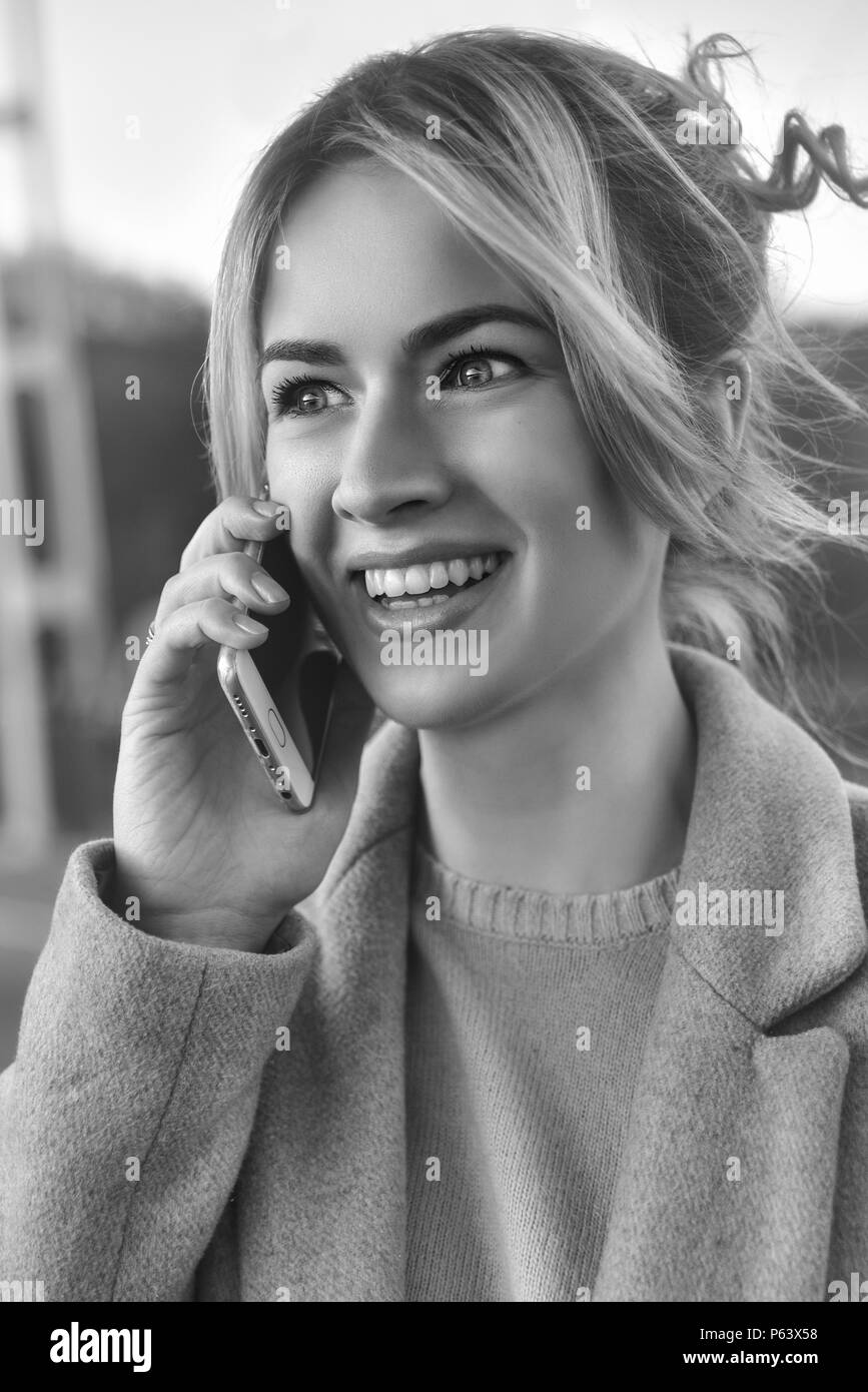 Cute smiling young woman talking on phone standing on the bride. Close up portrait Stock Photo