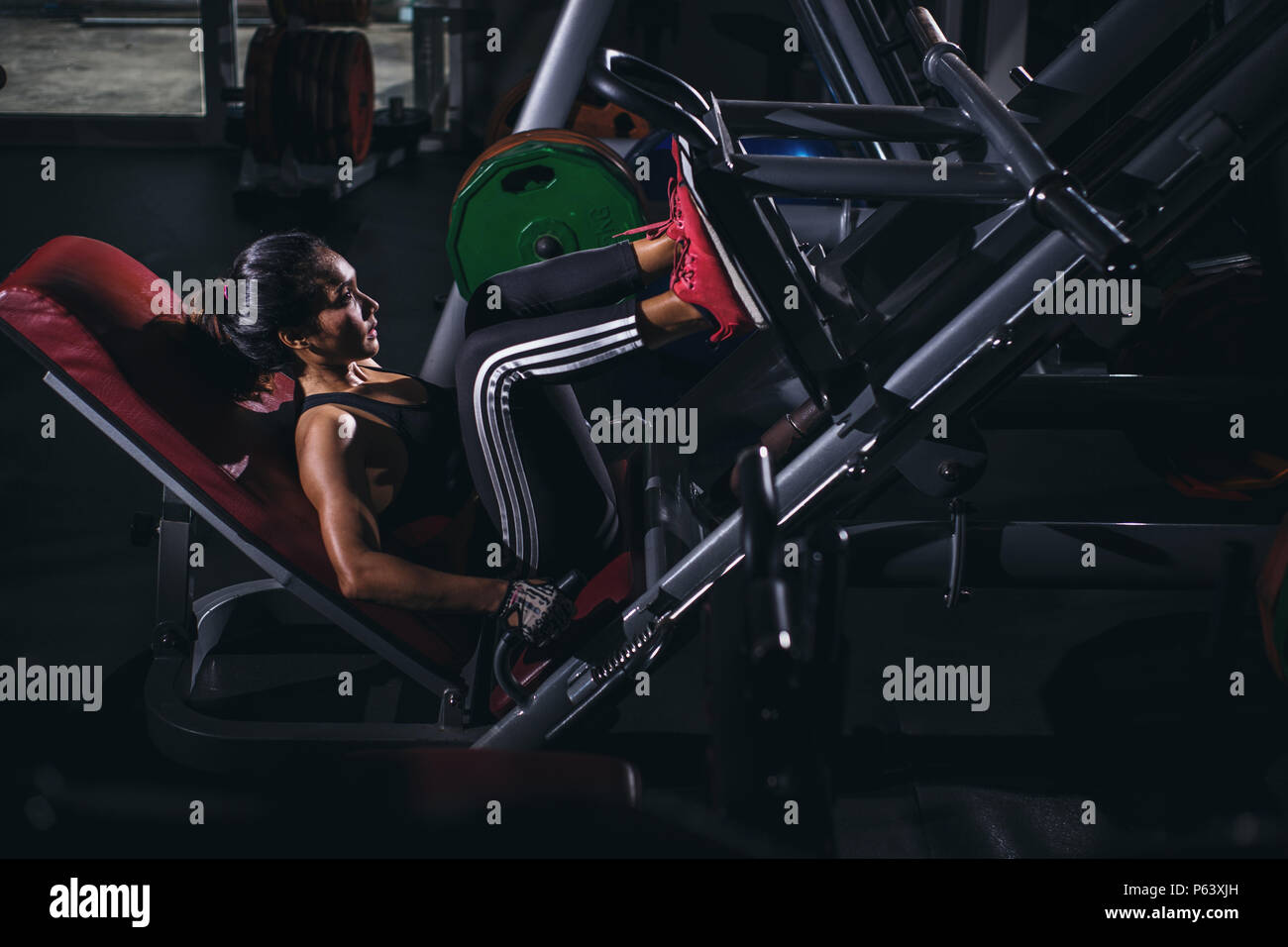 Strong Asia woman execute exercise with exercise-machine in gym. Stock Photo