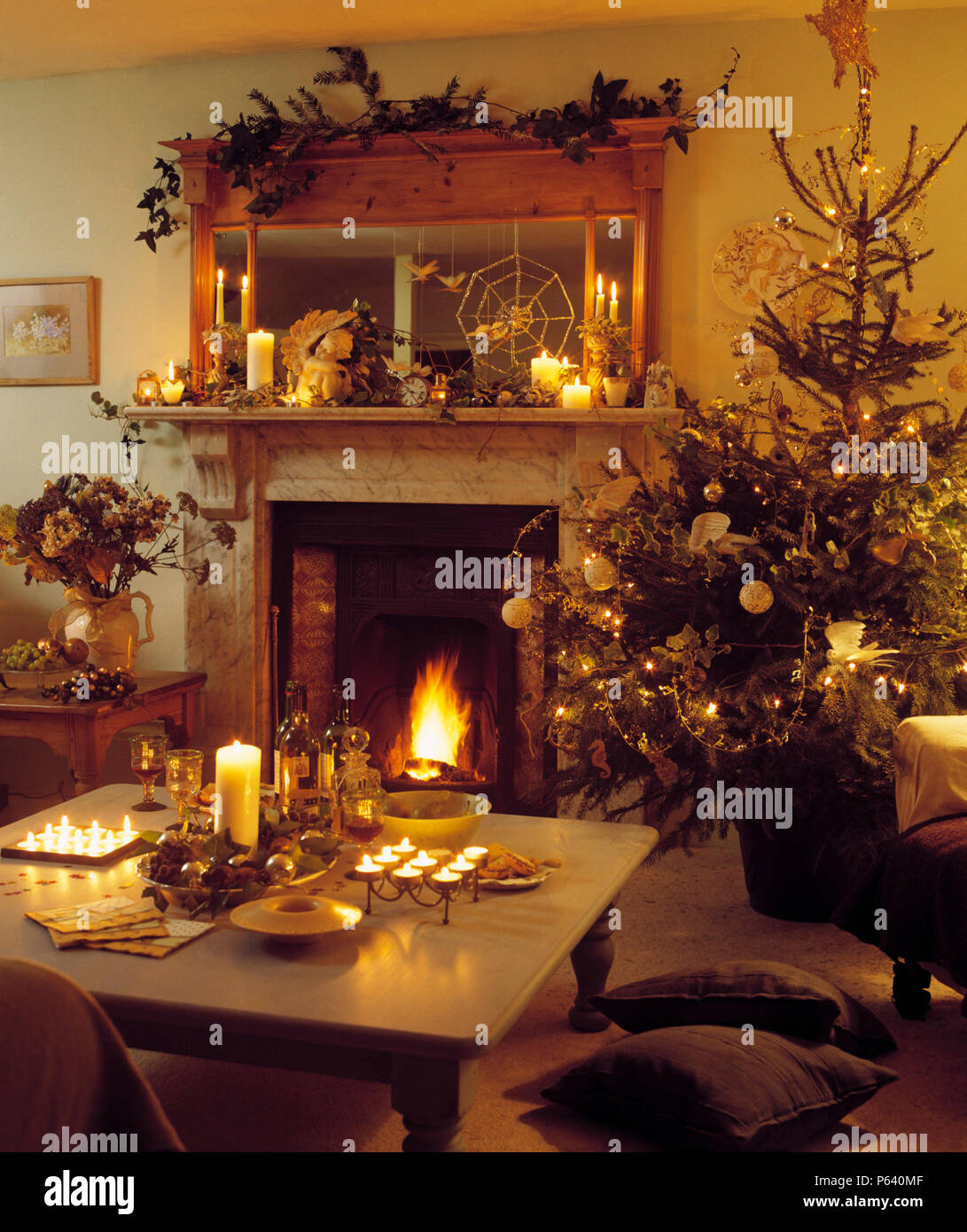 Country sitting room lit by candles and decorated for Christmas with tree  by fireplace with lighted fire Stock Photo - Alamy
