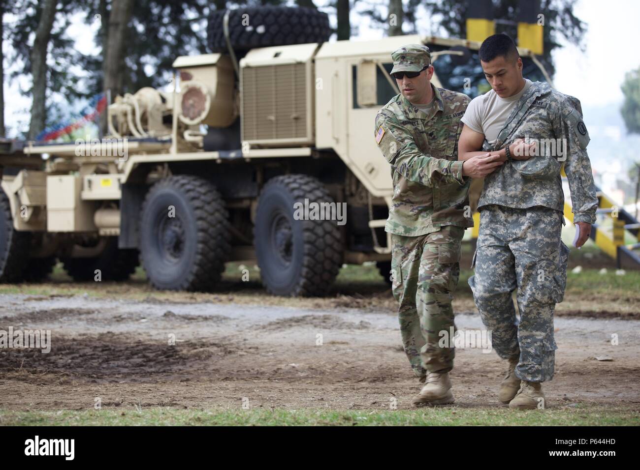 U.S. Army Spc. Brian Schwarts from the Medical Detachment helps Spc. Cesar Ahermado from the 115th Maintenance Company walk during a Mass Casualty Exercise as part of the Beyond The Horizon Operation at San Marcos, Guatemala, April 26, 2016. Task Force Red Wolf and Army South conducts Humanitarian Civil Assistance Training to include tactical level construction projects and Medical Readiness Training Exercises providing medical access and building schools in Guatemala with the Guatemalan Government and non-government agencies from 05MAR16 to 18JUN16 in order to improve the mission readiness of Stock Photo