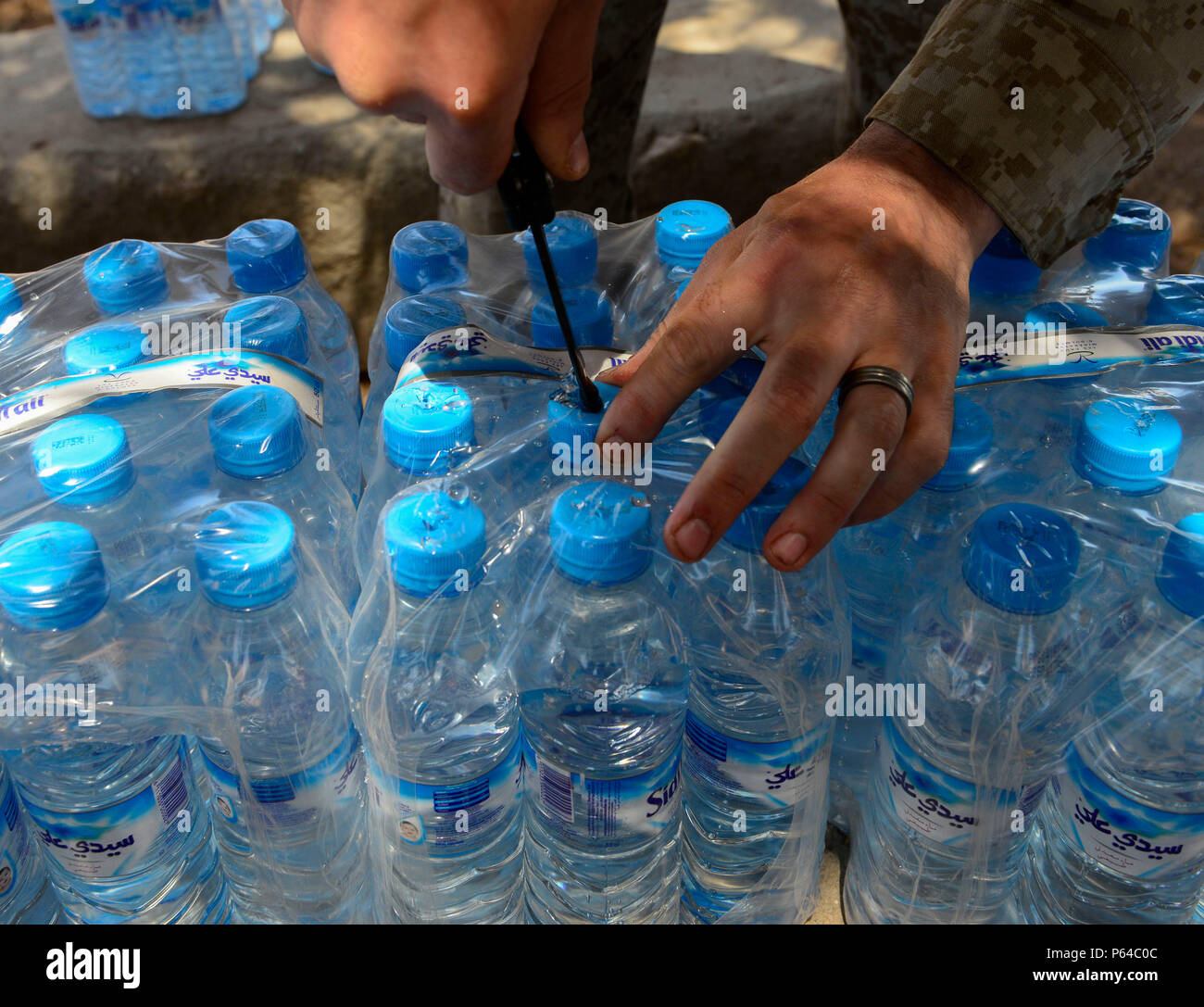 A U.S. Marine Corps Marine punches holes in the tops of water bottles prior to a non-lethal weapons class where the participants were sprayed with OC pepper spray during AFRICAN LION 16 at Tifnit, Kingdom of Morocco, April 23, 2016. The U.S. Marine Forces Europe-Africa and Kingdom of Morocco-led joint exercise provided familiarization with various military techniques from 11 different countries and provided an opportunity to become more familiar with allied nations’ tactics to ease synchronization.  (U.S. Air Force photo by Senior Airman Krystal Ardrey/Released) Stock Photo