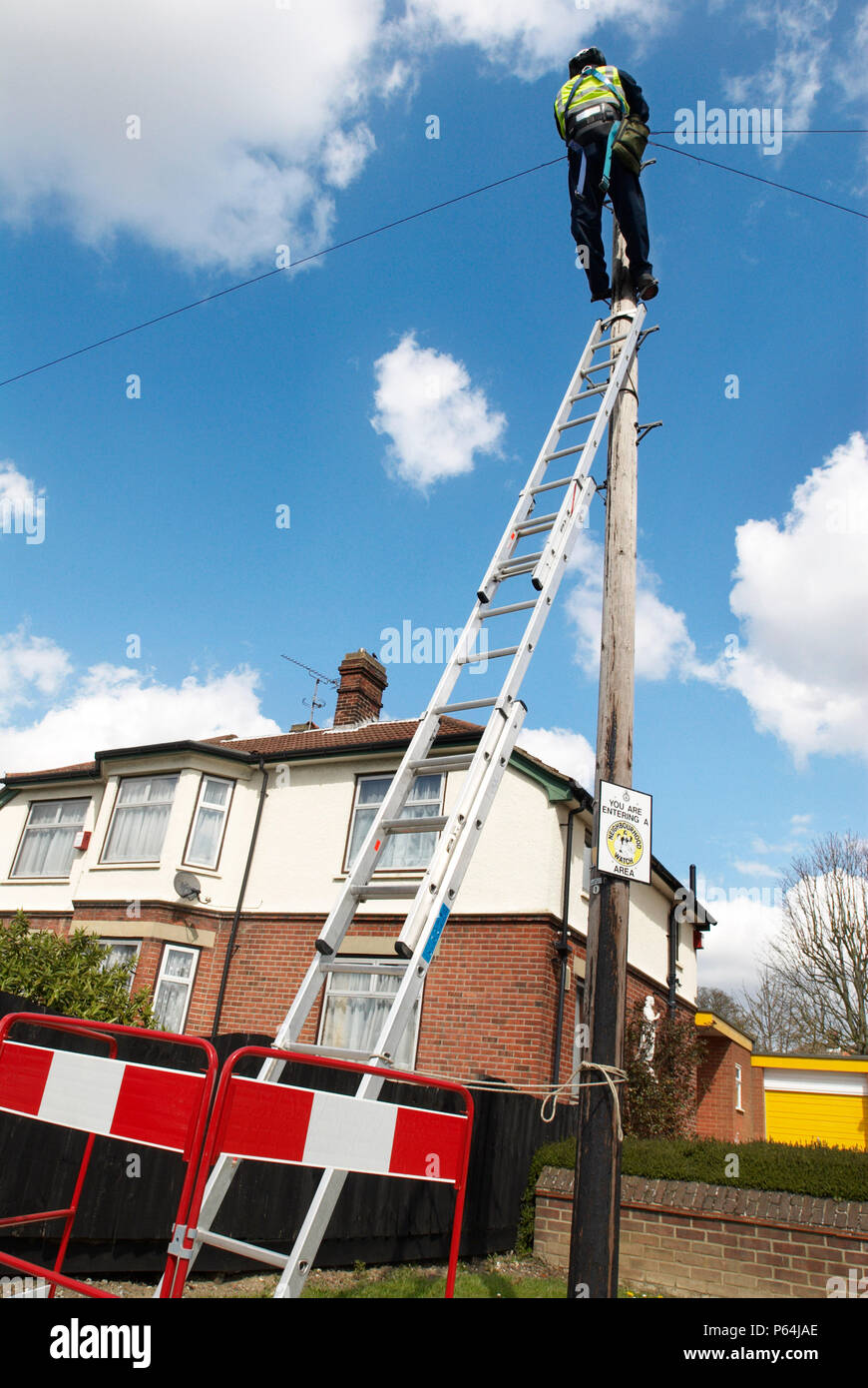 Telephone engineer on a ladder repairing residential lines, Ipswich