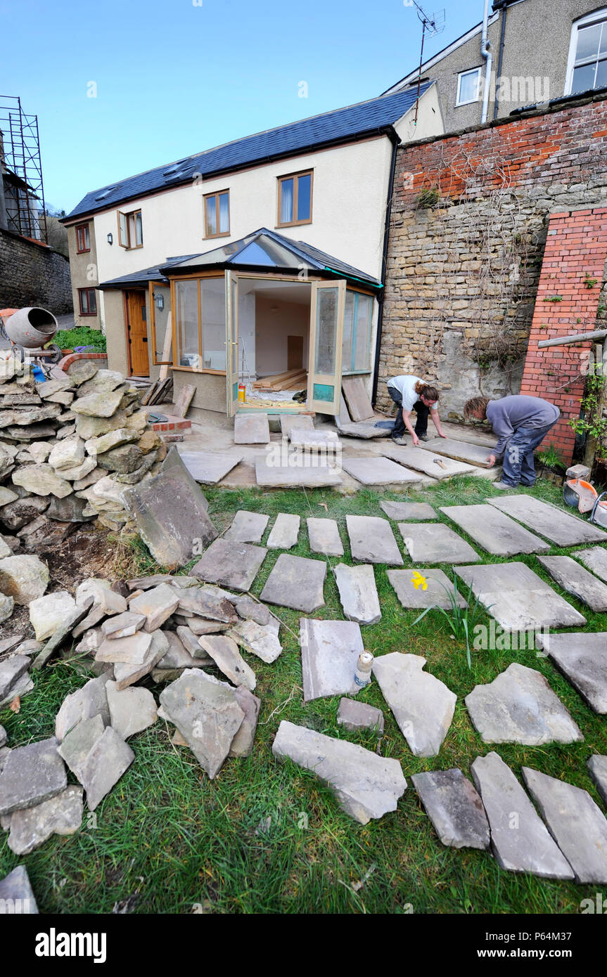 Builders lay out natural stone slabs in planning a patio, Gloucestershire UK Stock Photo