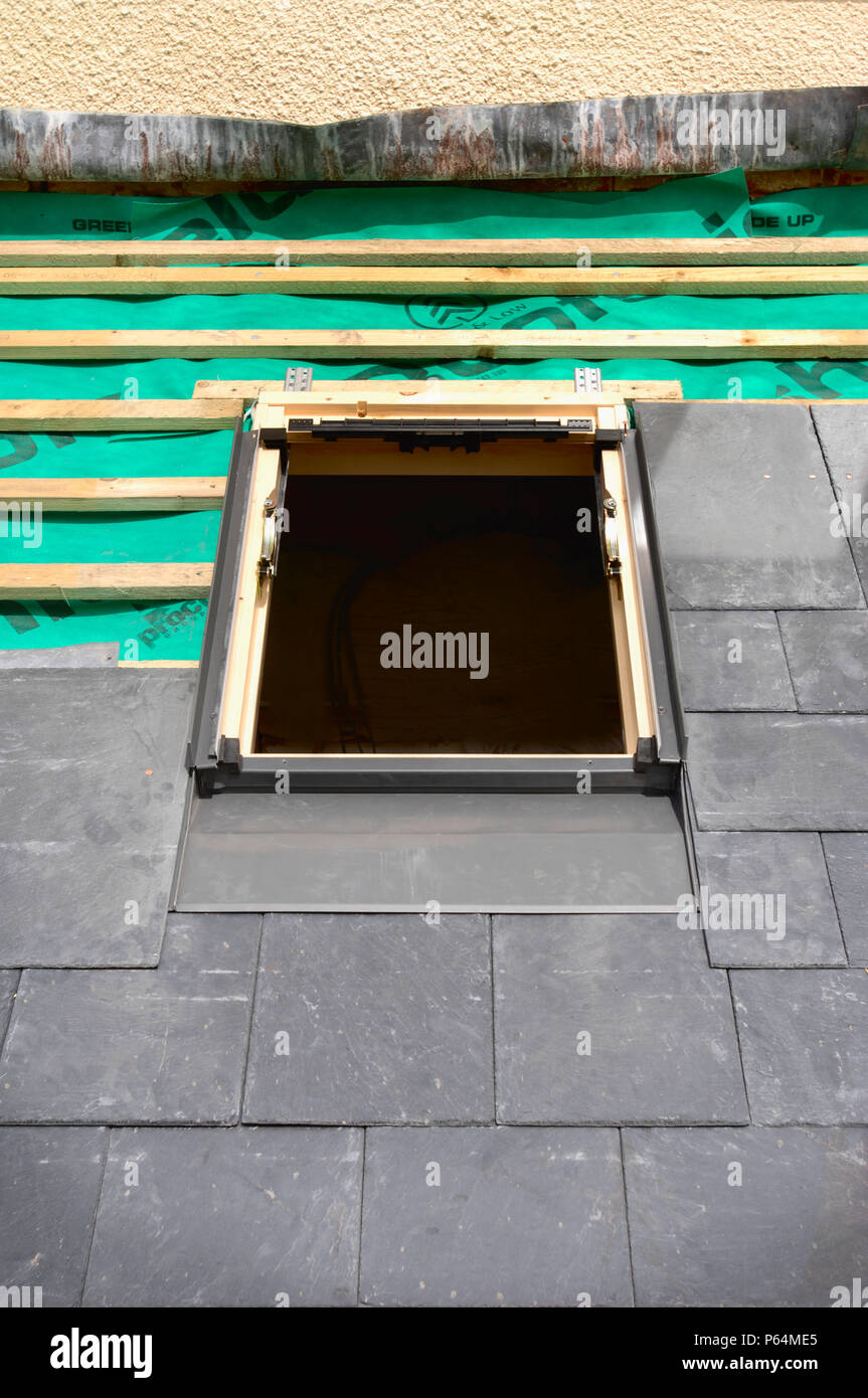 Fitting a velux window on a slate roof under construction showing the