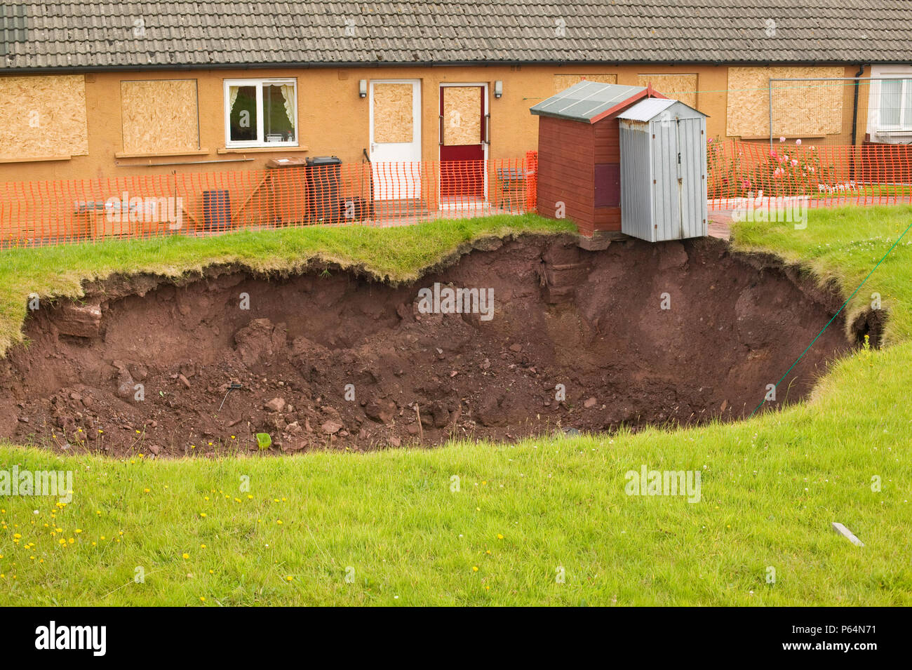 A massive hole opens up in a back garden in Egremont Cumbria as a result of mining subsidence when in June 2005 an old mine shaft opened up Stock Photo