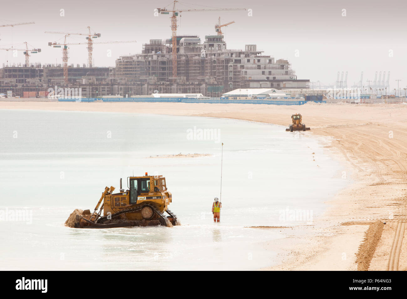 Workers creating a new beach resort on the Palm development in Dubai. Creating new sea front real estate is a questionable thing to do as climate chan Stock Photo