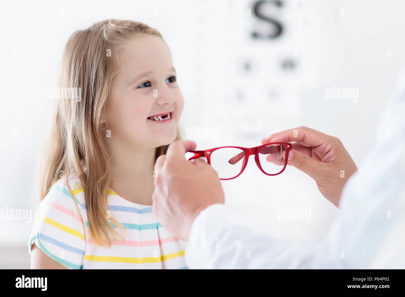 Child at eye sight test. Little kid selecting glasses at optician store