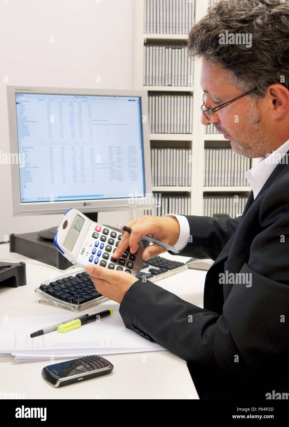Accountant at his desk working with calculator. Stock Photo