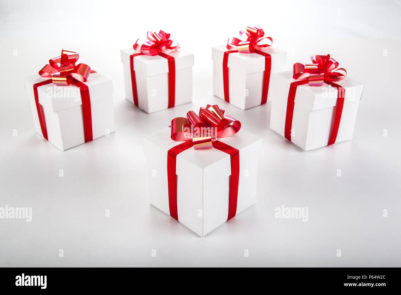 White gift boxes with red ribbons and bows on gray Stock Photo