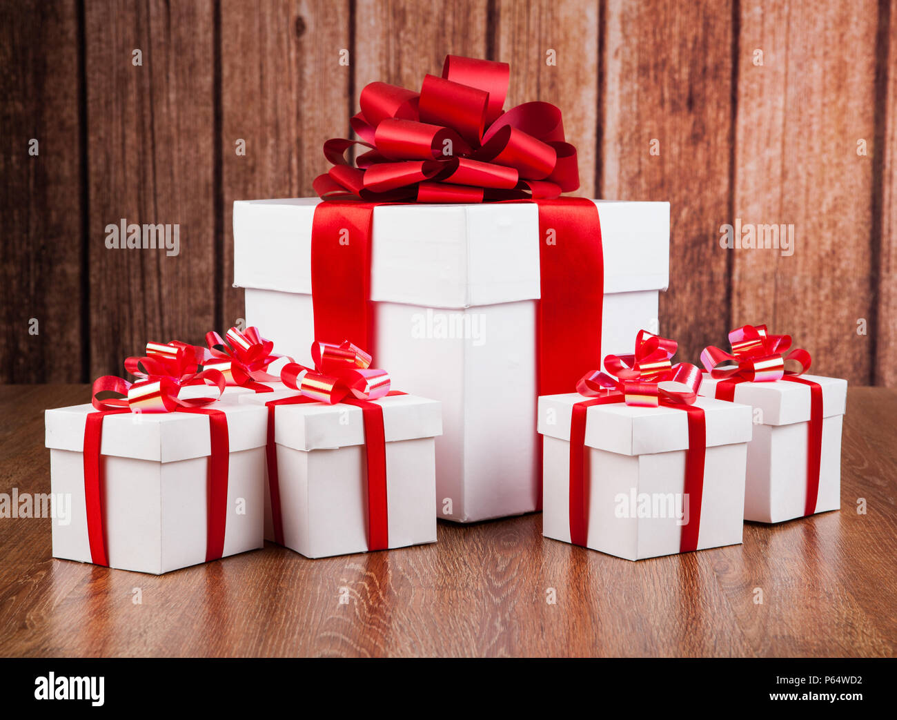 one large white gift box and white gift boxes on a wood background