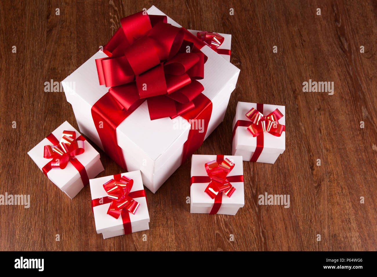 one large white gift box and white gift boxes on a wood background