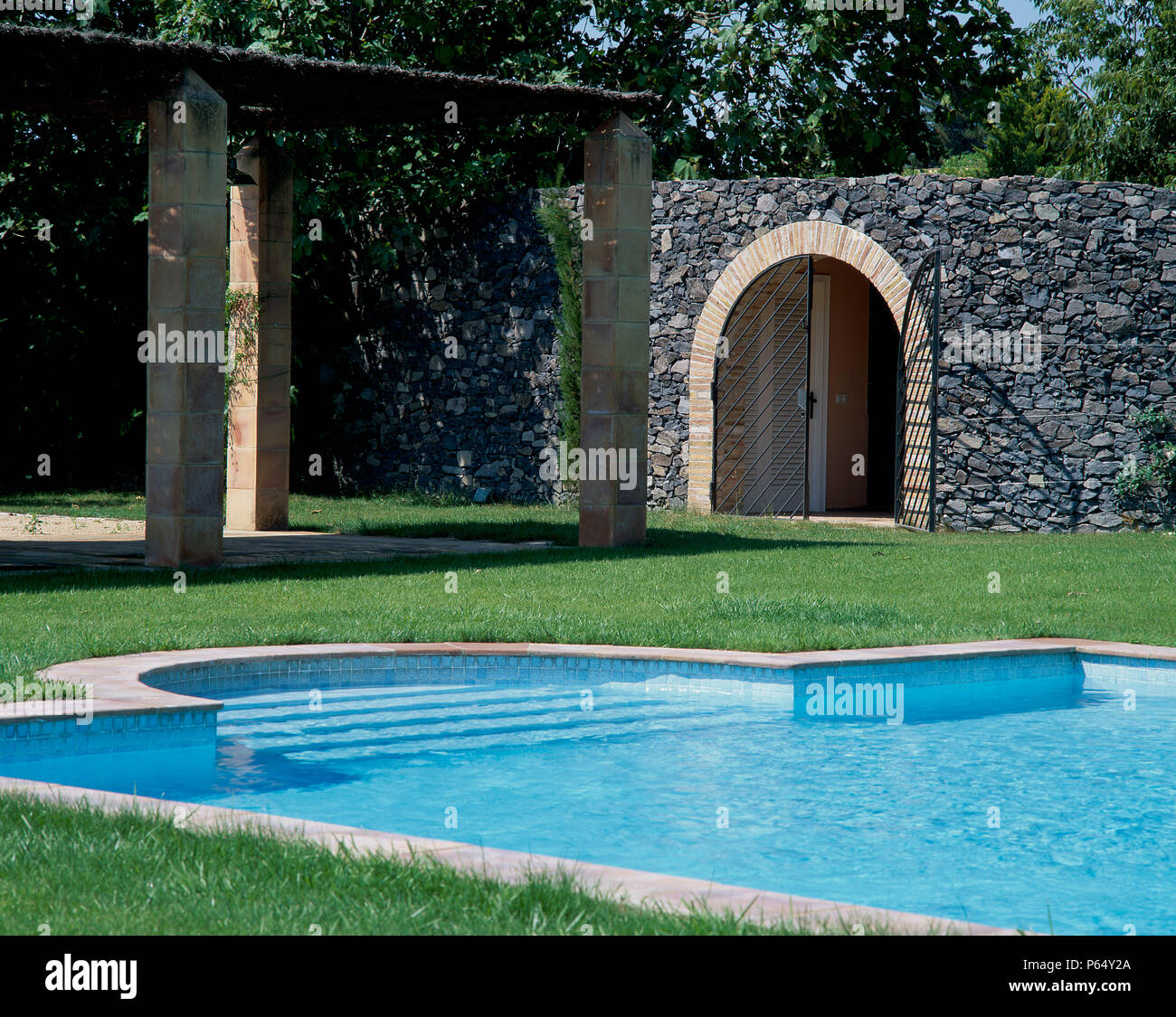 View a clean swimming pool beside a stony wall Stock Photo