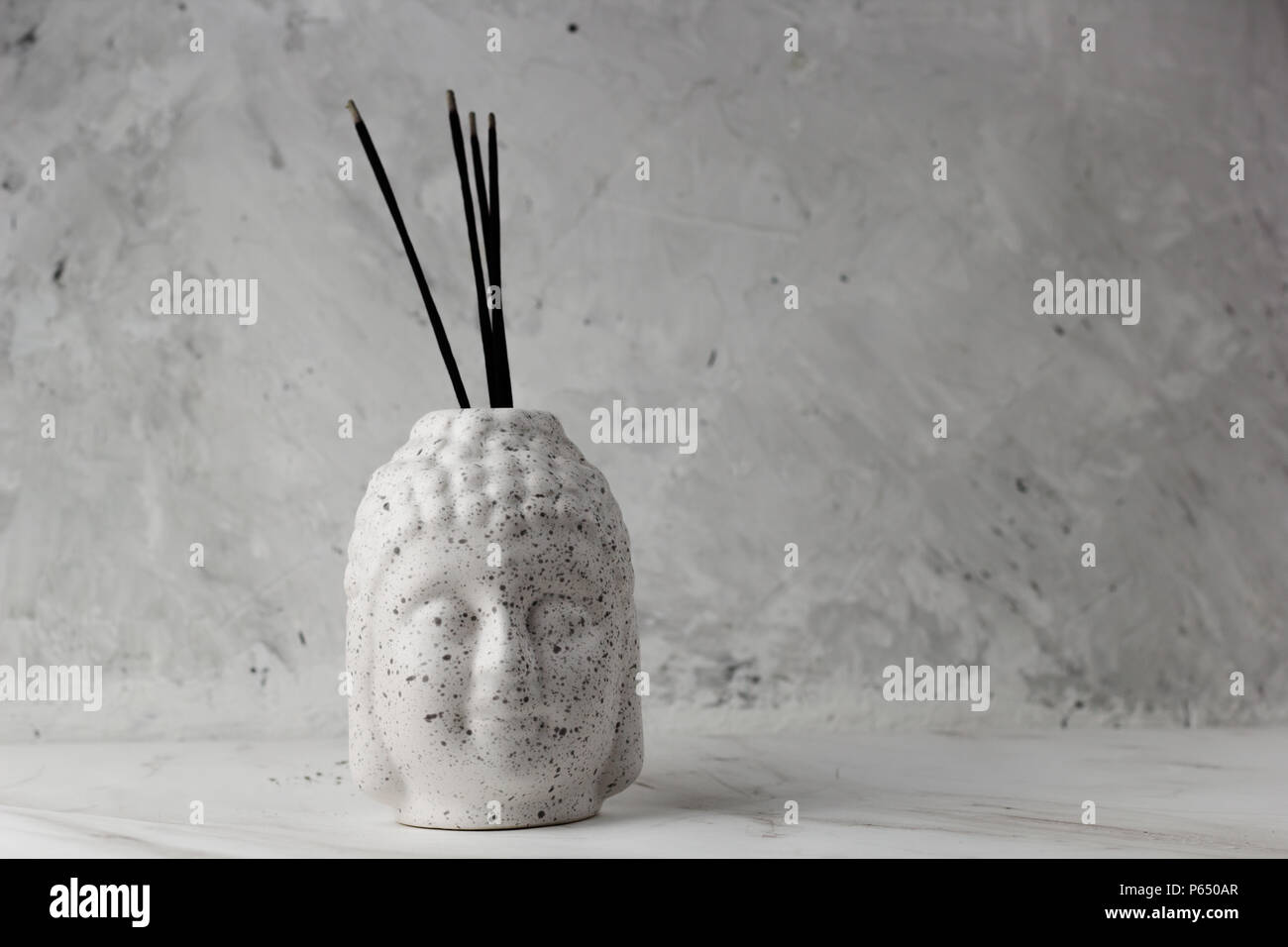 Buddha head with incense on a concrete background Stock Photo