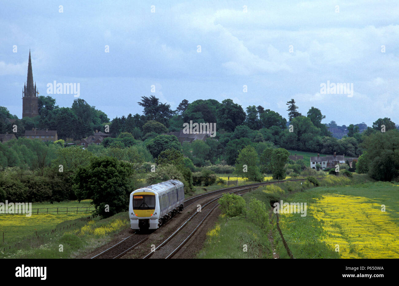 A Class 168 Chiltern Turbo DMU passes the delightful village of Kings Sutton in the Cherwell Valley. Stock Photo