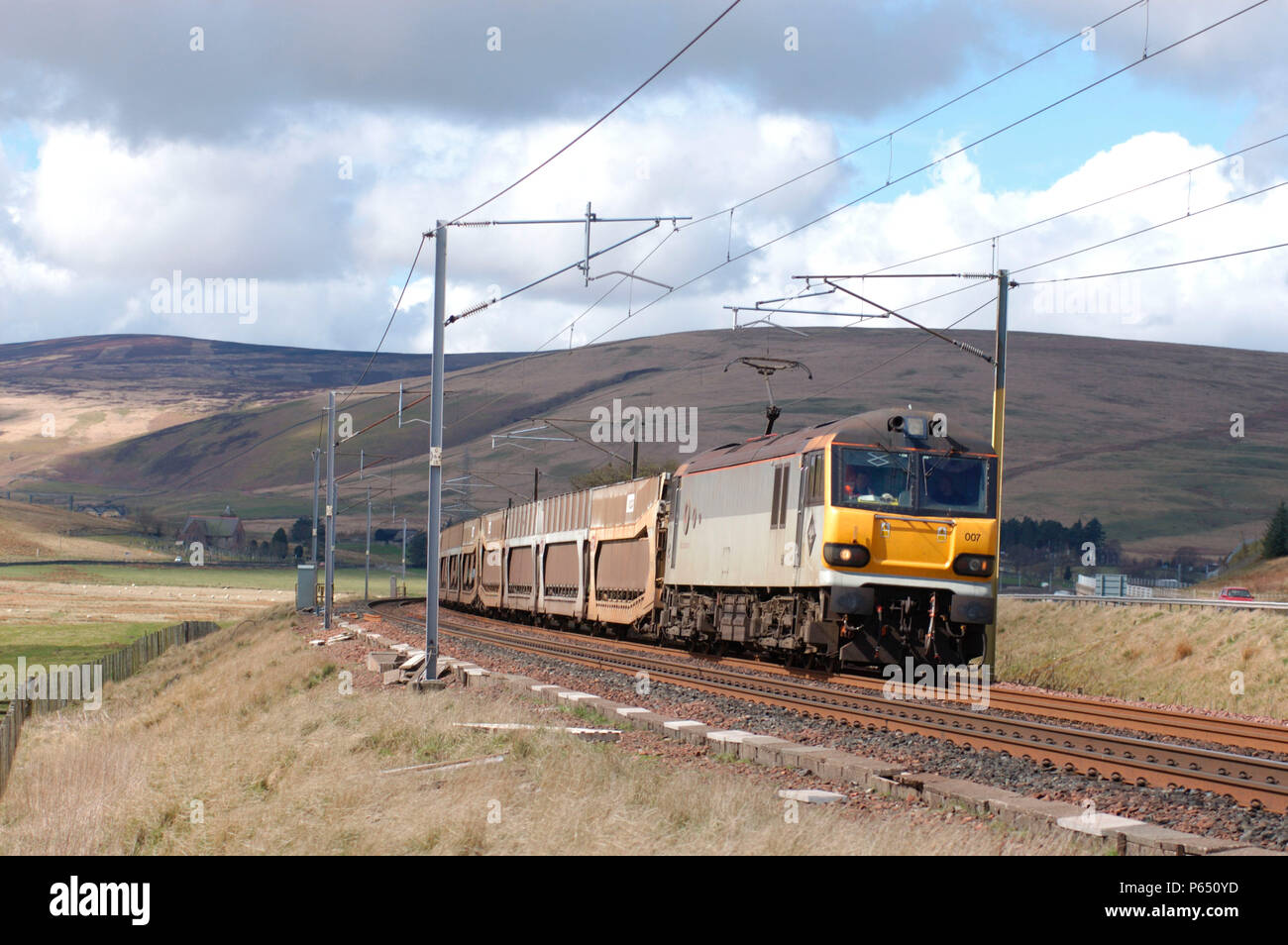 A Class 92 multi-voltage electric locomotive curves through the Upper Clyde valley on the ascent of Beattock with a Mossend - Carlisle Enterprise serv Stock Photo