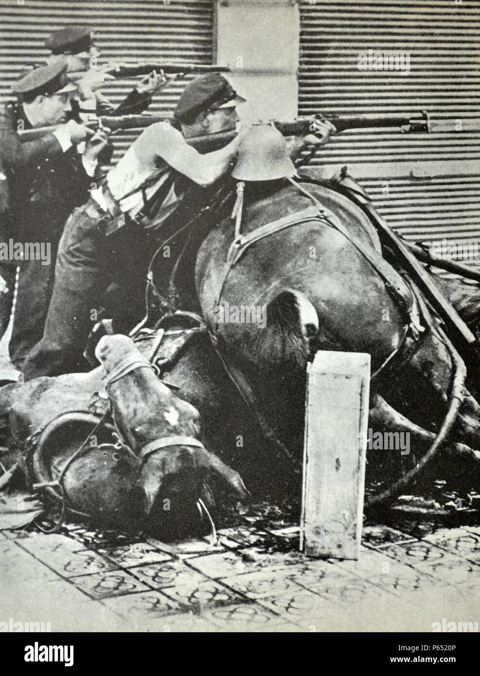 Three republican fighters take aim with rifles, behind a barricade made up of dead horses. Barcelona 1937, during the Spanish civil war 1938 Stock Photo
