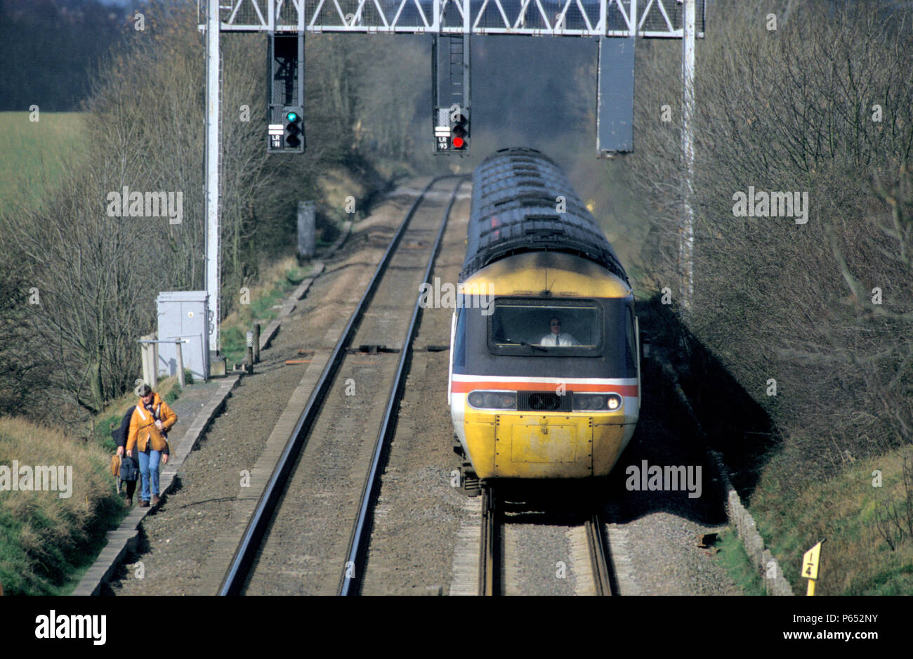 Midland Main Line in Leicestershire with a Class 43 HST heading south passing under the signal gantry as track workers make their way on foot. C 1995 Stock Photo