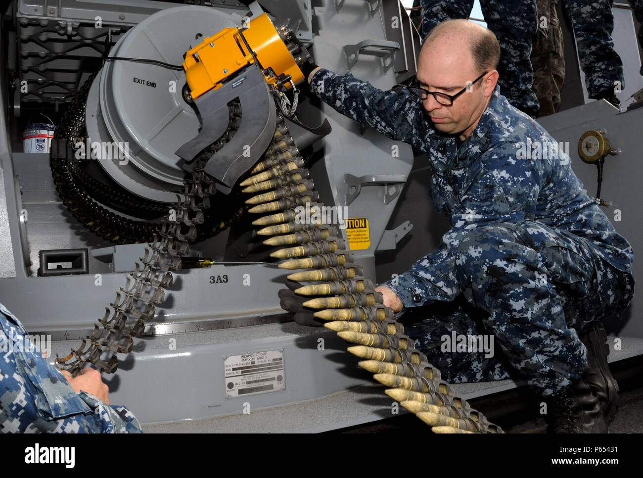 A Fire Controlman guides dummy rounds into the Close-In Weapons System ...