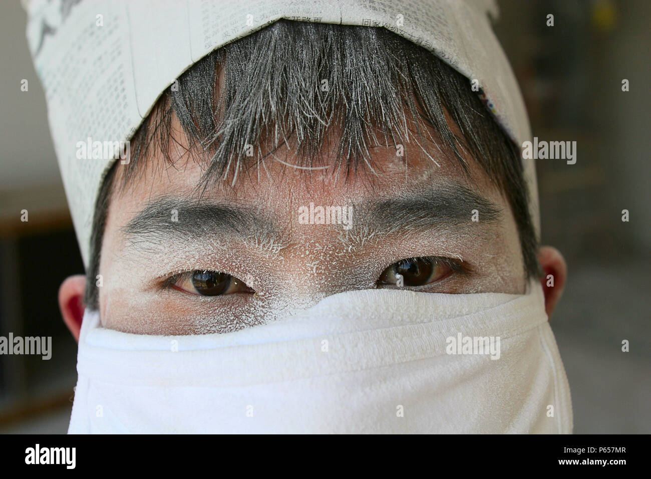 A Worker Wearing A Cotton Mask Pauses From Work Sanding Ceiling