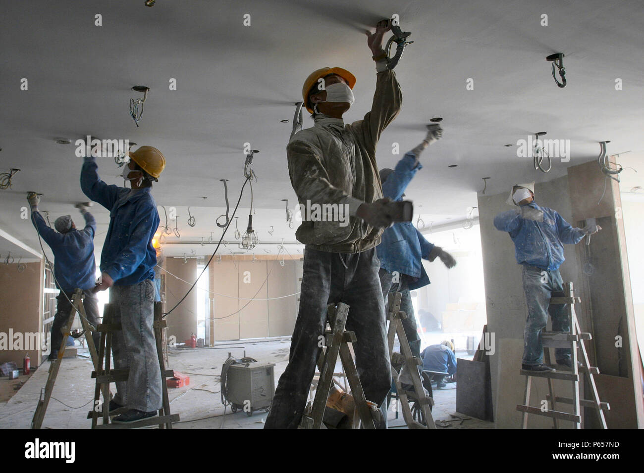 Chinese Workers Sanding Ceiling Plaster In A New Office