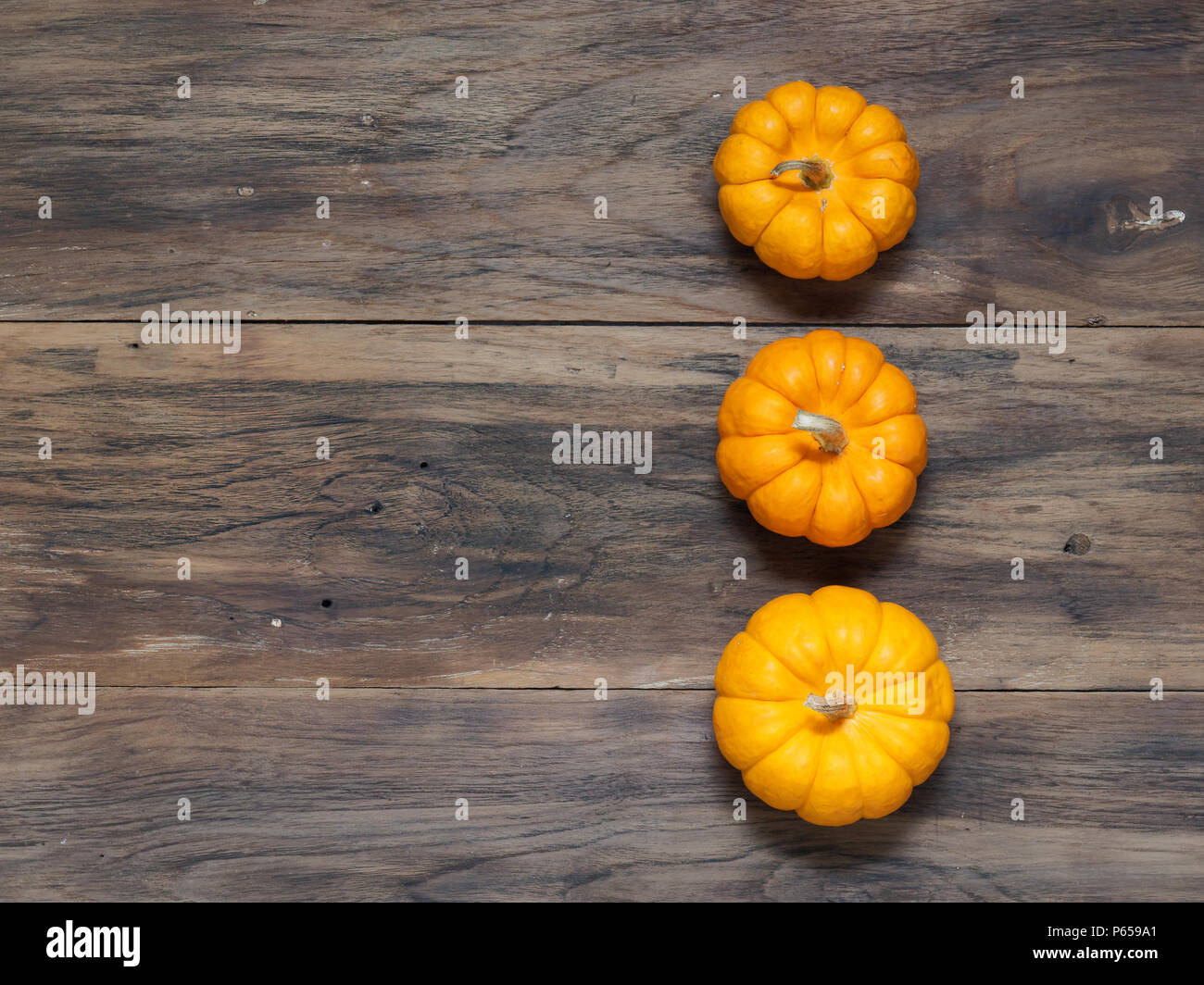 Three orange pumpkins in big, medium, and small size put vertically on ...