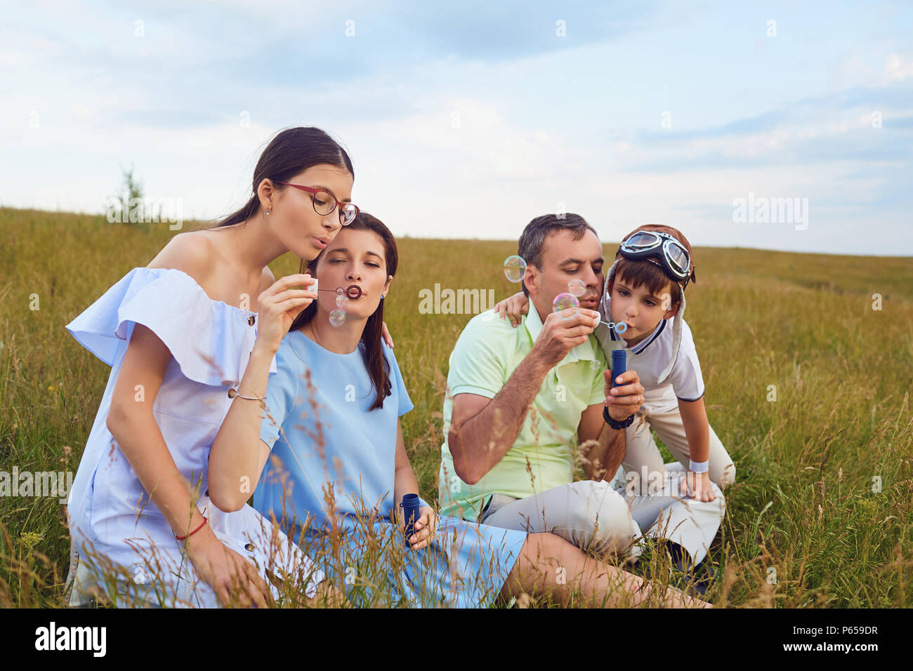 A happy family plays with blurred bubbles in nature Stock Photo