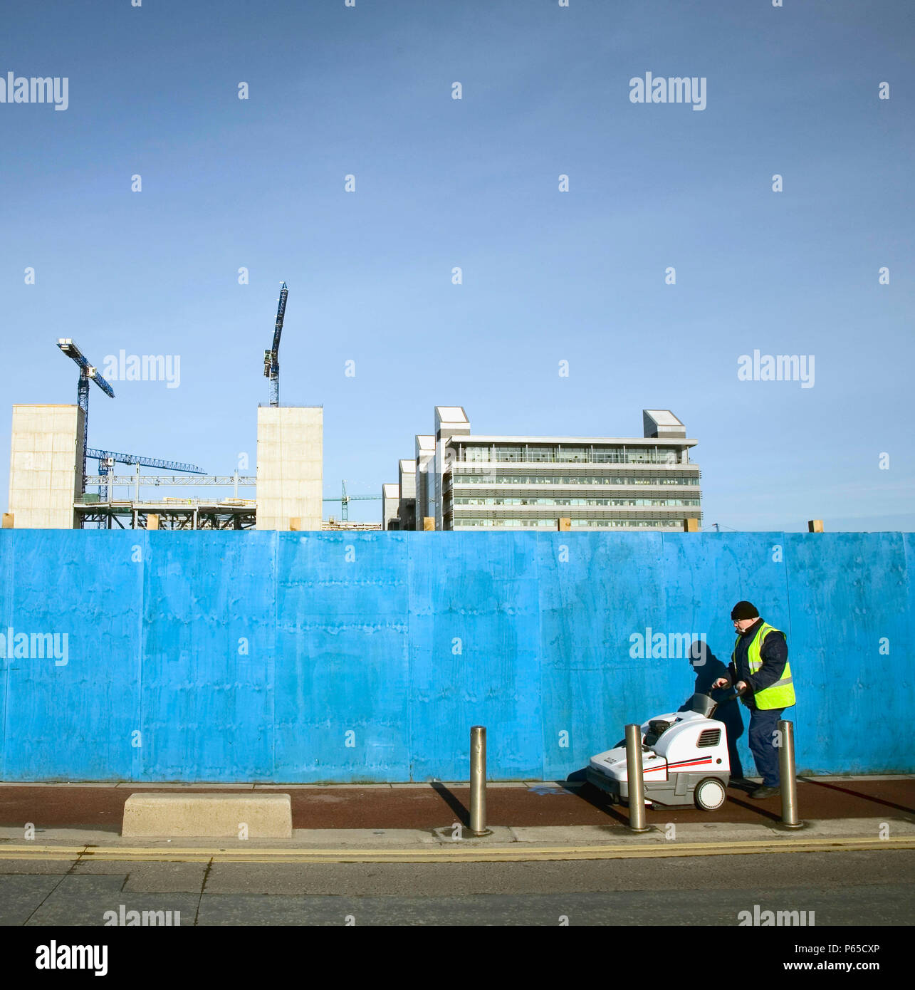 Street cleaner passing construction site beside River Liffey, Dublin, Ireland, feb 2008 Stock Photo