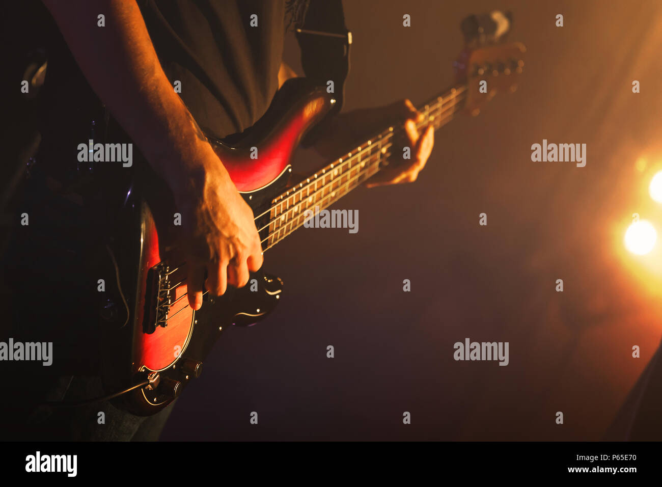 Guitarist plays on of bass guitar in scenic lights, soft selective focus, live music theme Stock Photo