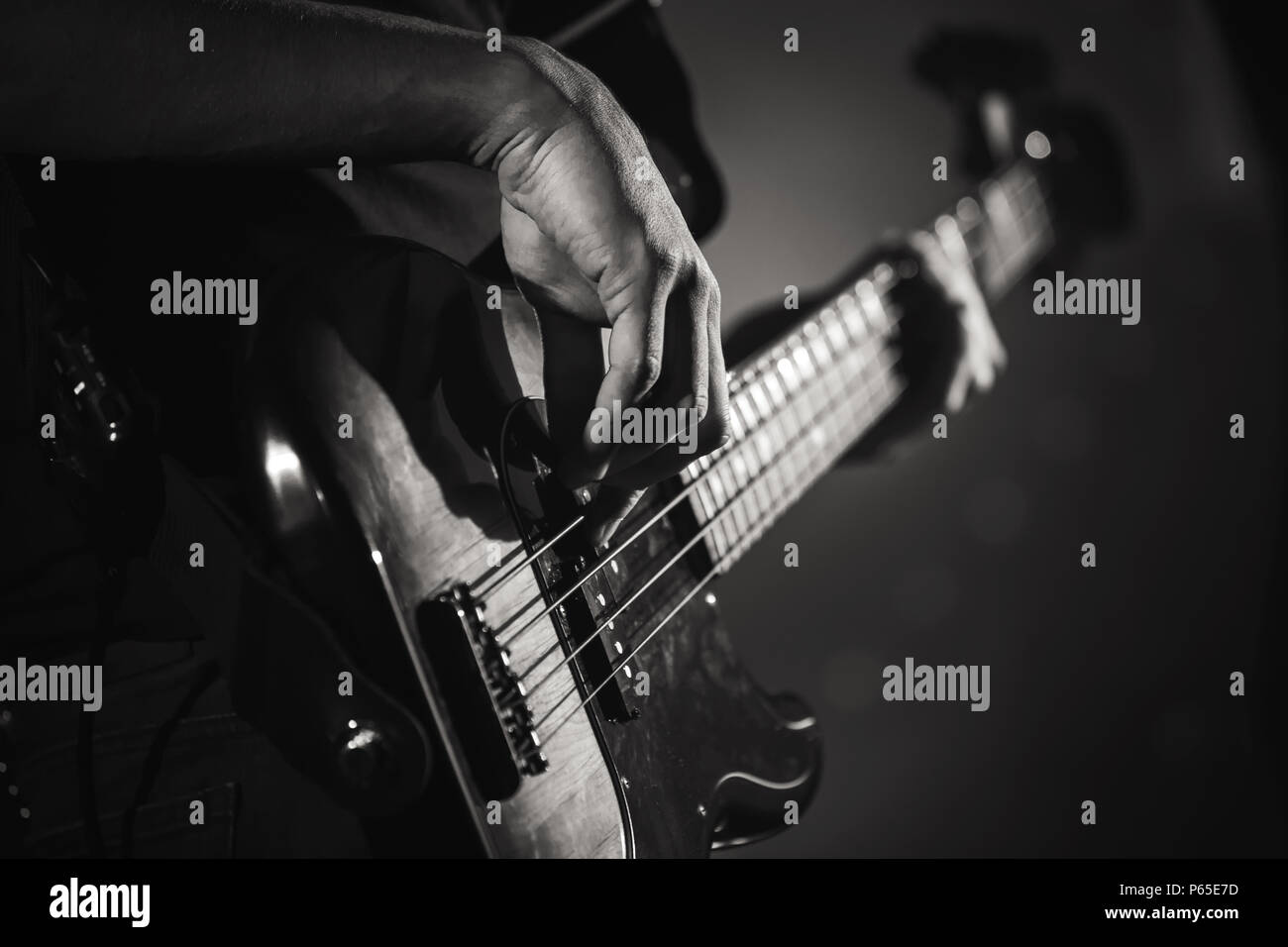 Electric bass guitar player hands, live music theme, close up black and white photo Stock Photo